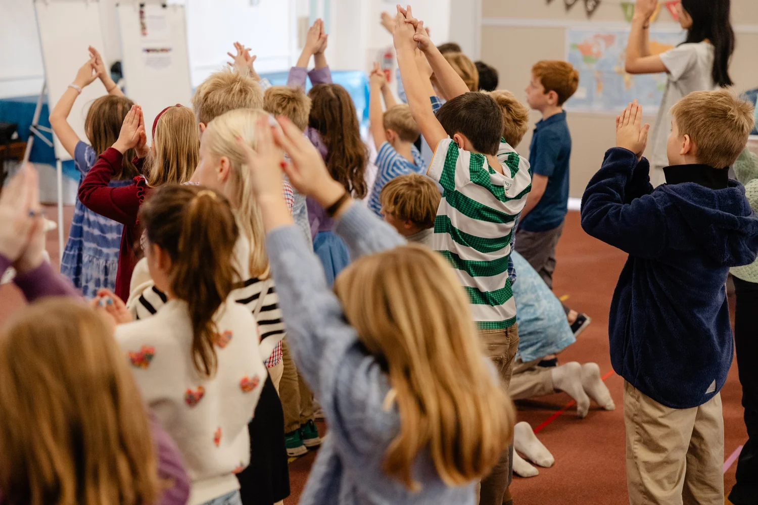 Children raise their hands together during Sunday School worship