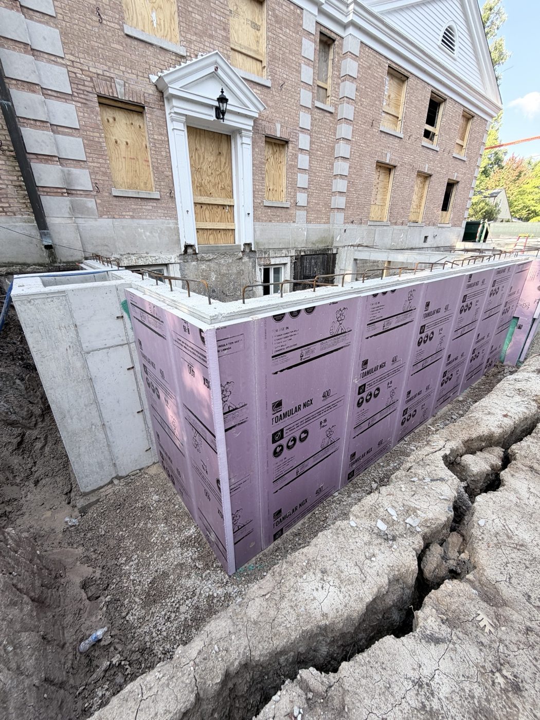 Foundation walls wrapped in pink waterproofing along the north side of the church