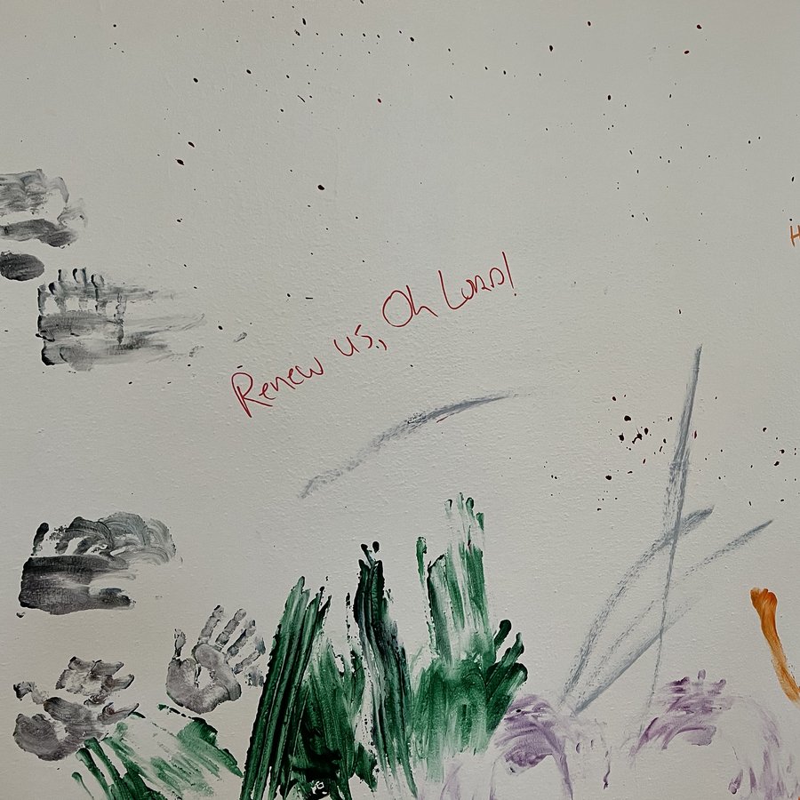 Painted handprints and the words "Renew us, Oh Lord!" on the West Hall wall