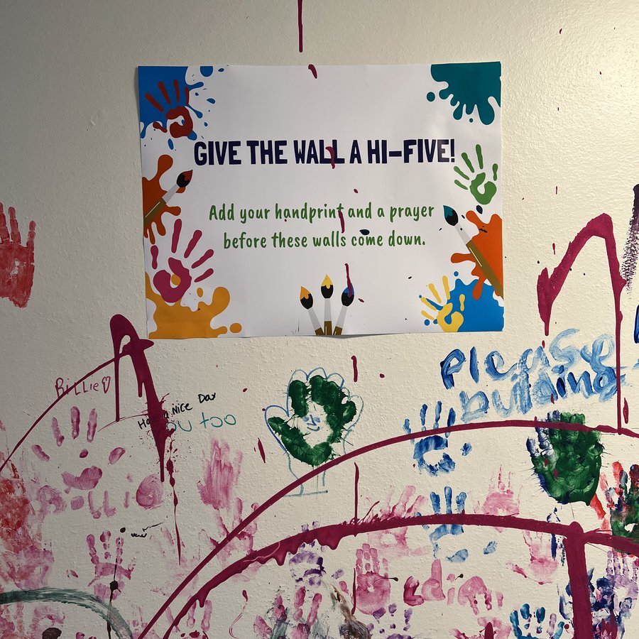 "Give the wall a hi-five!" sign surrounded by children&rsquo;s colorful handprints