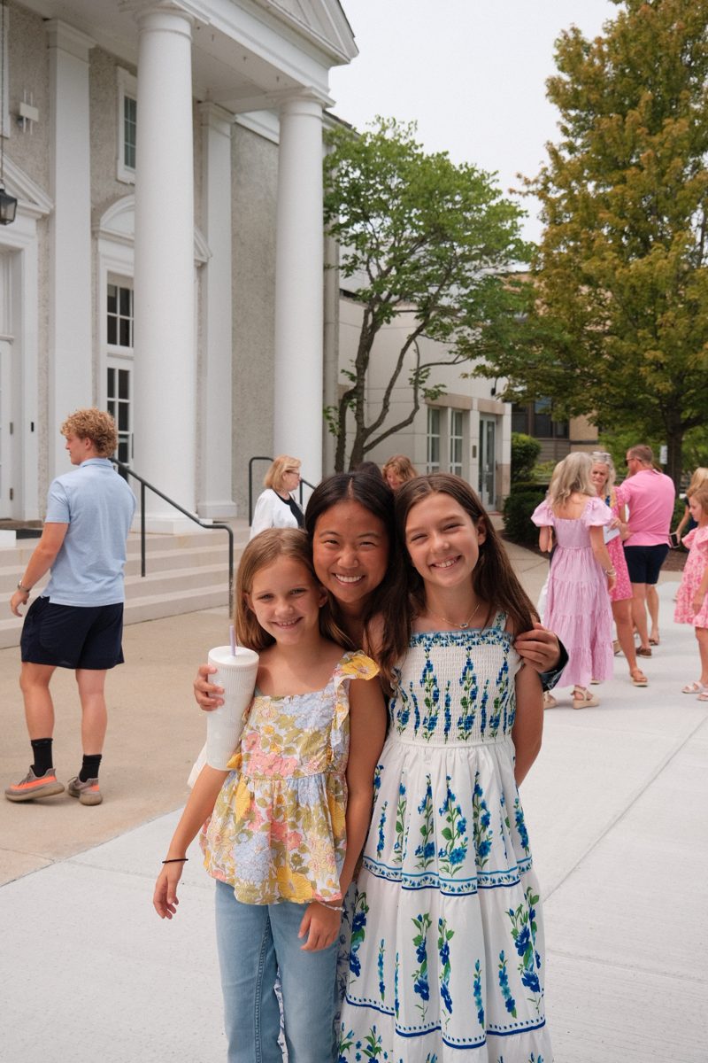 Three girls smiling together outside the church after Sunday worship